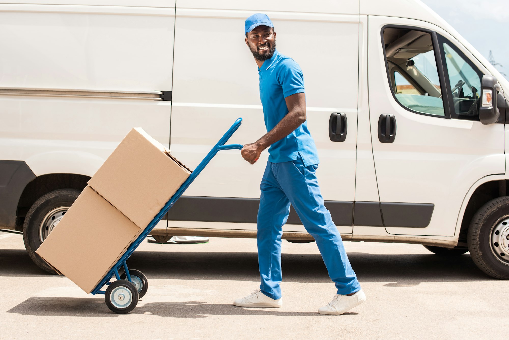 side view of african american delivery man with cart and boxes